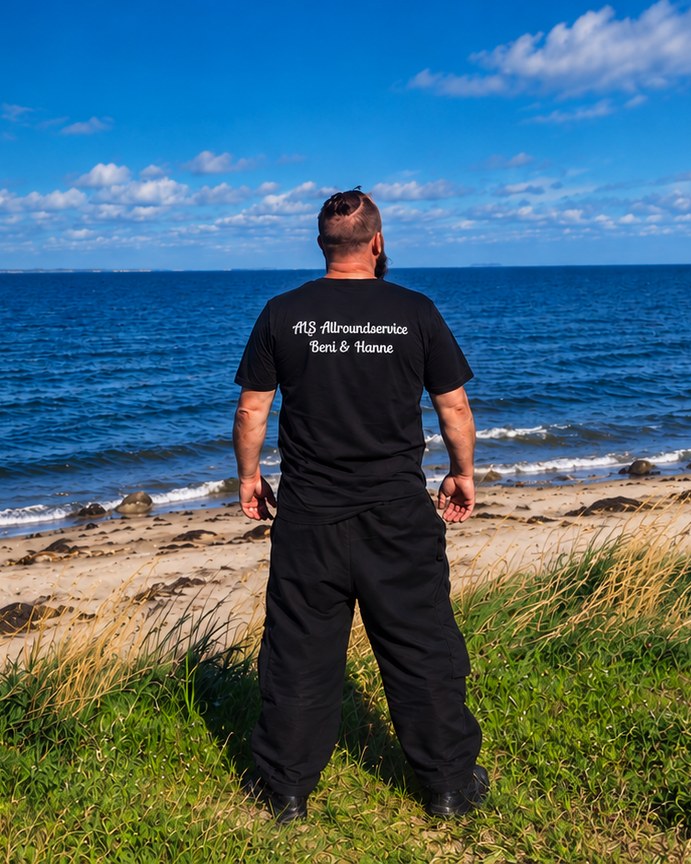Beni von ALS Allroundservice am Strand auf Als, im T-Shirt mit Firmenschriftzug